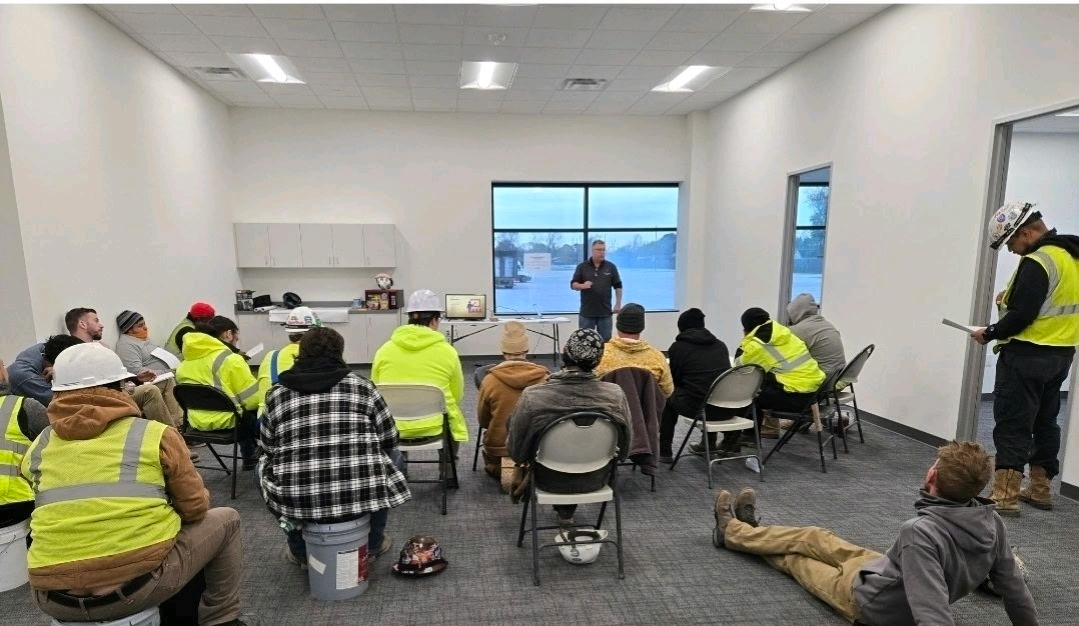 Full classroom of workers in hi-vis gear during an on-site OSHA safety training session